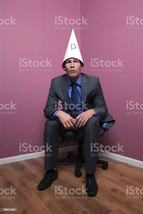 Businessman Sat In Corner Wearing Dunce Hat Stock Photo Download