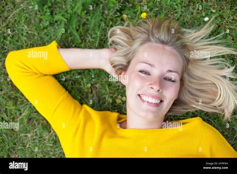 Portrait Of A Pretty Blonde Woman Lying Down In Park Smiling At Camera Stock Photo Alamy
