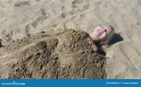 Petite Fille D une Chevelure Blonde Obtenant Enterrée En Sable Photo stock Image du ayant