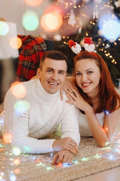 Premium Photo A Happy Married Couple Is Lying On The Floor Near The Christmas Tree At Home