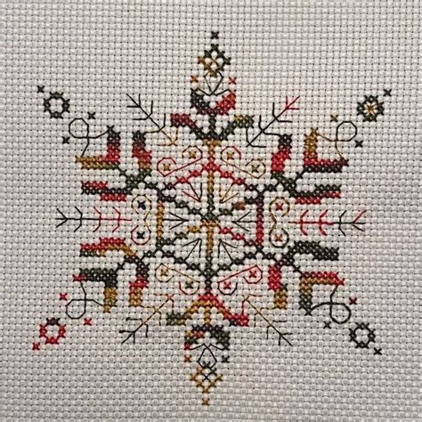 A Cross Stitched Snowflake Is Shown In Red Yellow And Black