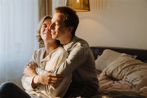 Jeune Couple Gay Embrassant Et Souriant Assis Au Lit Image Stock Image Du Gens Treinte