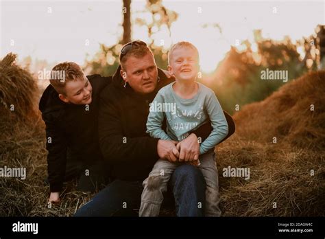 Father Posing With His Two Blonde Sons While Sitting On The Pile In Autumn Stock Photo Alamy