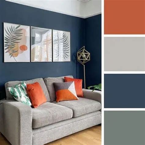 A Living Room With Blue Walls Orange And Gray Pillows On The Couches