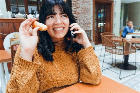 Joven Latina Feliz Hablando Por Tel Fono Y Comiendo Comida Venezolana Tequeno Foto Premium