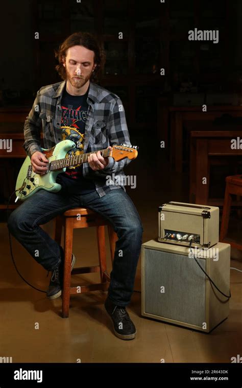 Bearded Guitarist Playing An Electric Guitar With An Amplifier Stock