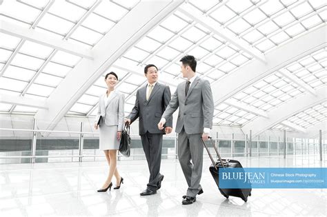 Chinese Business Partners On The Move In Airport Lobby High Res Stock