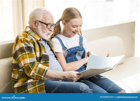 Grandfather And Granddaughter Reading Book Together At Home Stock Image