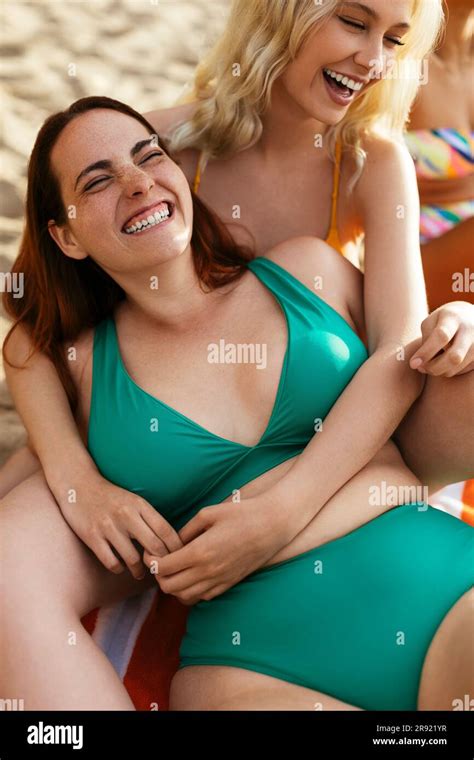 Woman Wearing Green Bikini Laughing With Friend At Beach Stock Photo