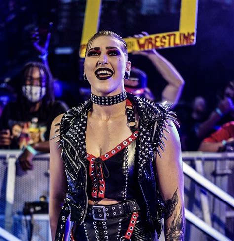 A Woman With Tattoos And Piercings On Her Chest Holding A Sign In Front