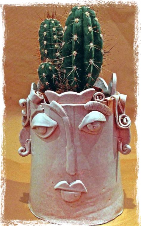 A Potted Plant With A Face Drawn On It S Side And Two Cacti In The