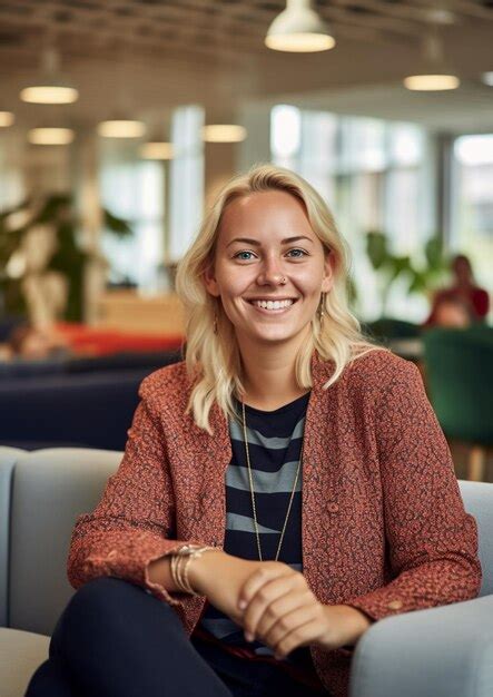 Une femme blonde souriante est assise dans un café avec une plante verte en arrière plan