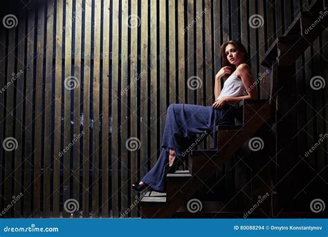 Sensual Brunette Sitting On Staircase Holding A Hand Near Face Stock