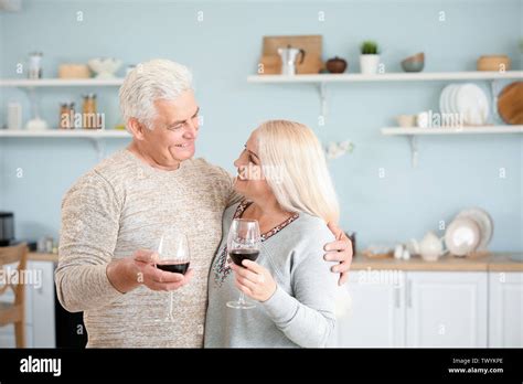 Happy Mature Couple Drinking Wine In Kitchen Stock Photo Alamy