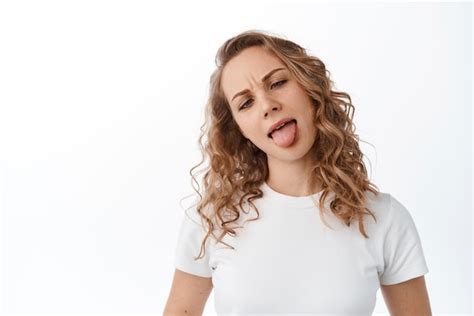 Amusante Fille Blonde Montrant La Langue Et Les Visages Stupides Plissant Les Yeux Debout Sur