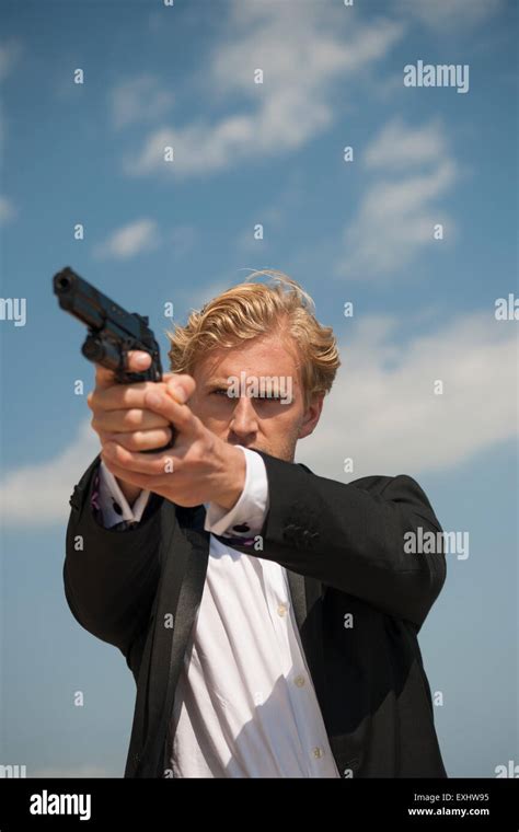 Man Aiming A Handgun Holding The Gun With Both Hands Wearing A Black
