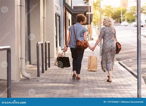 Happy Lesbian Couple Walking In The City Carrying Shopping Bags Stock Photo Image Of Casual