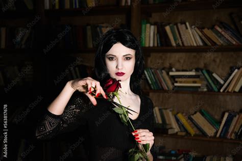 Beautiful Brunette Girl Cosplay Morticia Addams With Red Lips And Nails Holding Red Rose And
