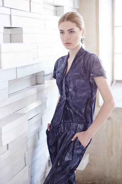 Fille blonde en costume bleu posant près du mur artistique Photo Gratuite