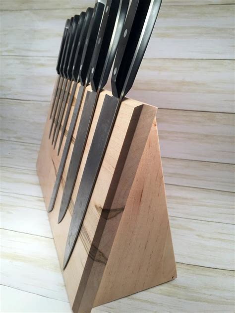 A Set Of Knives Sitting On Top Of A Wooden Block In The Shape Of A Pyramid