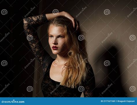 Fashionable Blonde Female Model In Black Bodysuit Posing In The Studio Looking At The Side