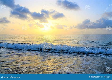 A Gentle Wave Washes Over The Coastal Shoreline At Sunrise Stock Photo