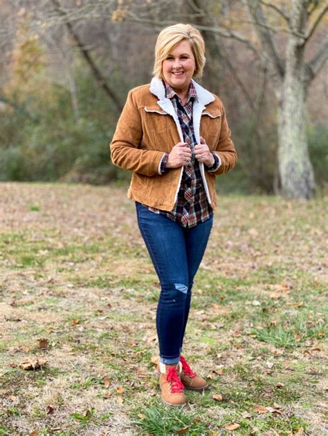 a woman is walking in the grass with her jacket on and she has red shoes