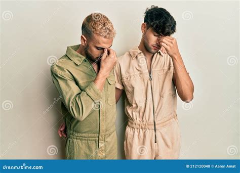 Homosexual Gay Couple Standing Together Wearing Casual Jumpsuit Tired Rubbing Nose And Eyes