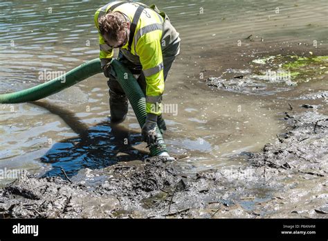 A Worker Using A Suction Pump To Remove Mud And Silt In A Lake Stock