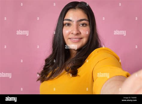 Beautiful Latina Woman Taking A Selfie In Studio With Pink Background Chubby Woman Stock Photo