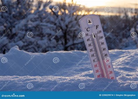 Thermometer On Snow Shows Low Temperatures In Celsius Or Farenheit On