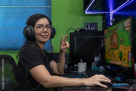 Mujer mediana edad latina con lentes jugando en línea en su habitación ganando Stock Photo