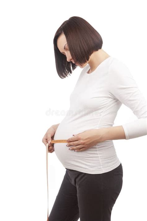 Cute Pregnant Brunette Woman Posing With Measurement Tape In White Shirt While Taking Dimensions