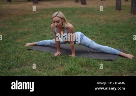 A Blonde Woman In A Stylish Blue Activewear Set Practices The Front Splits Pose Hanumanasana On