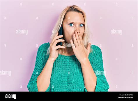 Belle Femme Blonde Caucasienne Ayant La Conversation Sur Le Smartphone Couvrant La Bouche Avec