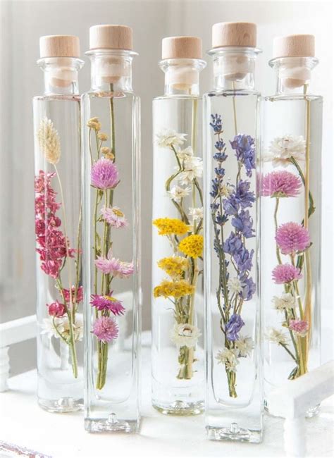 Three Glass Bottles Filled With Different Types Of Flowers