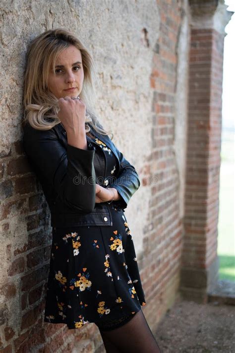 Femme Blonde Caucasienne Originaire De Royaume Uni En Robe Posant Devant Un Mur En Brique Photo