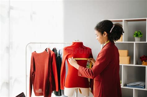 Calm Curly Brunette Dark Skinned Woman On Desk In Office Of Fashion