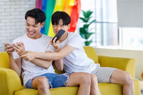 Two Asian Cheerful Teenager Male Gay Men Lover Couple Partner Sitting Smiling On Sofa Holding