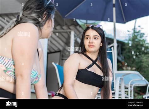 Two Very Happy Latina Friends Talking In Bikinis By The Hotel Pool Enjoying Their Vacation