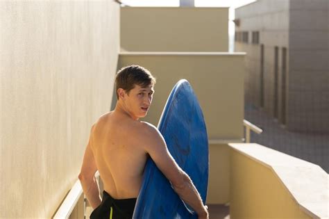 Premium Photo A Man With Naked Torso Holding A Surfboard Looking Over His Shoulder