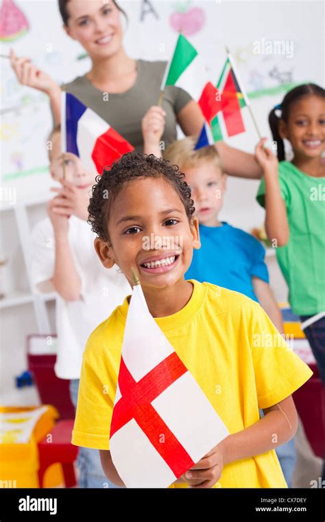 Grupo de niños en edad preescolar y maestra con banderas en el aula