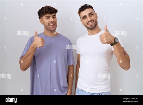 Homosexual Gay Couple Standing Over White Background Doing Happy Thumbs