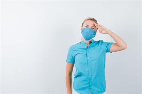 Junge blonde Frau zeigt Grußgeste in Freizeitkleidung Maske und sieht selbstbewusst aus looking