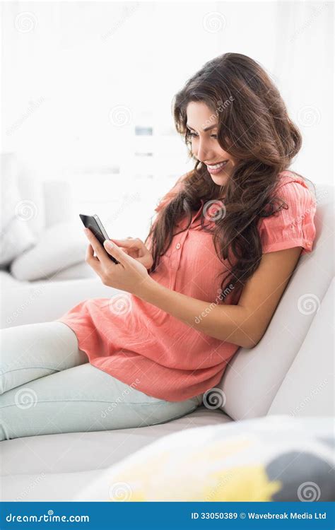 Happy Brunette Sitting On Her Couch Using Her Smartphone Stock Image Image Of Abode Beautiful