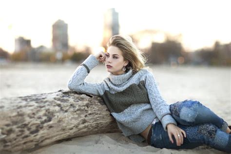 Une Jeune Fille Blonde Avec La Robe En Cuir Noire Se Reposant Sur Le Trottoir Devant Le Mur De