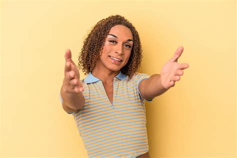Una Joven Transexual Latina Aislada De Fondo Amarillo Se Siente Confiada Dando Un Abrazo A La
