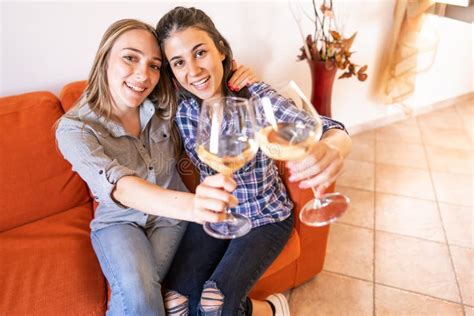 Two Happy Lesbian Girls Toasting With Champagne On Sofa Looking At Camera Celebrating Freedom Of