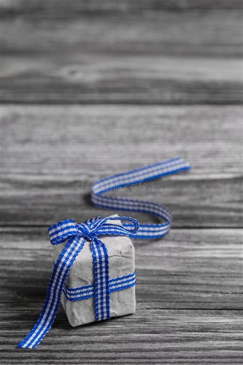 T Box With Blue Checked Ribbon On Wooden Grey Background Stock