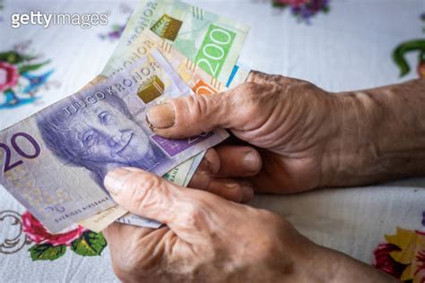 A Swedish Pensioner Holds A Bunch Of Low Denomination Banknotes In Her